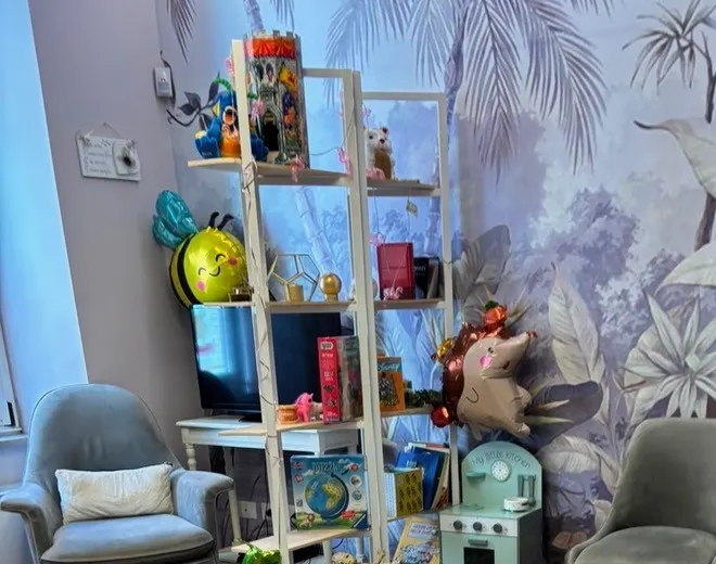 L'angolo dei bambini nella sala d'attesa: la parete dipinta a foglie, gli scaffali coi giochi, le poltroncine