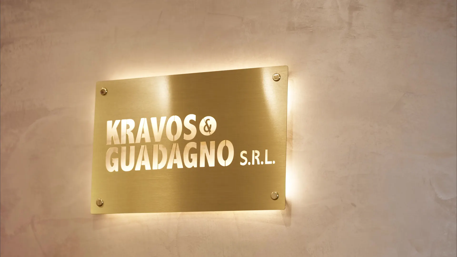 La targa d'ottone «Kravos & Guadagno S.r.l.» illuminata all'ingresso dello studio